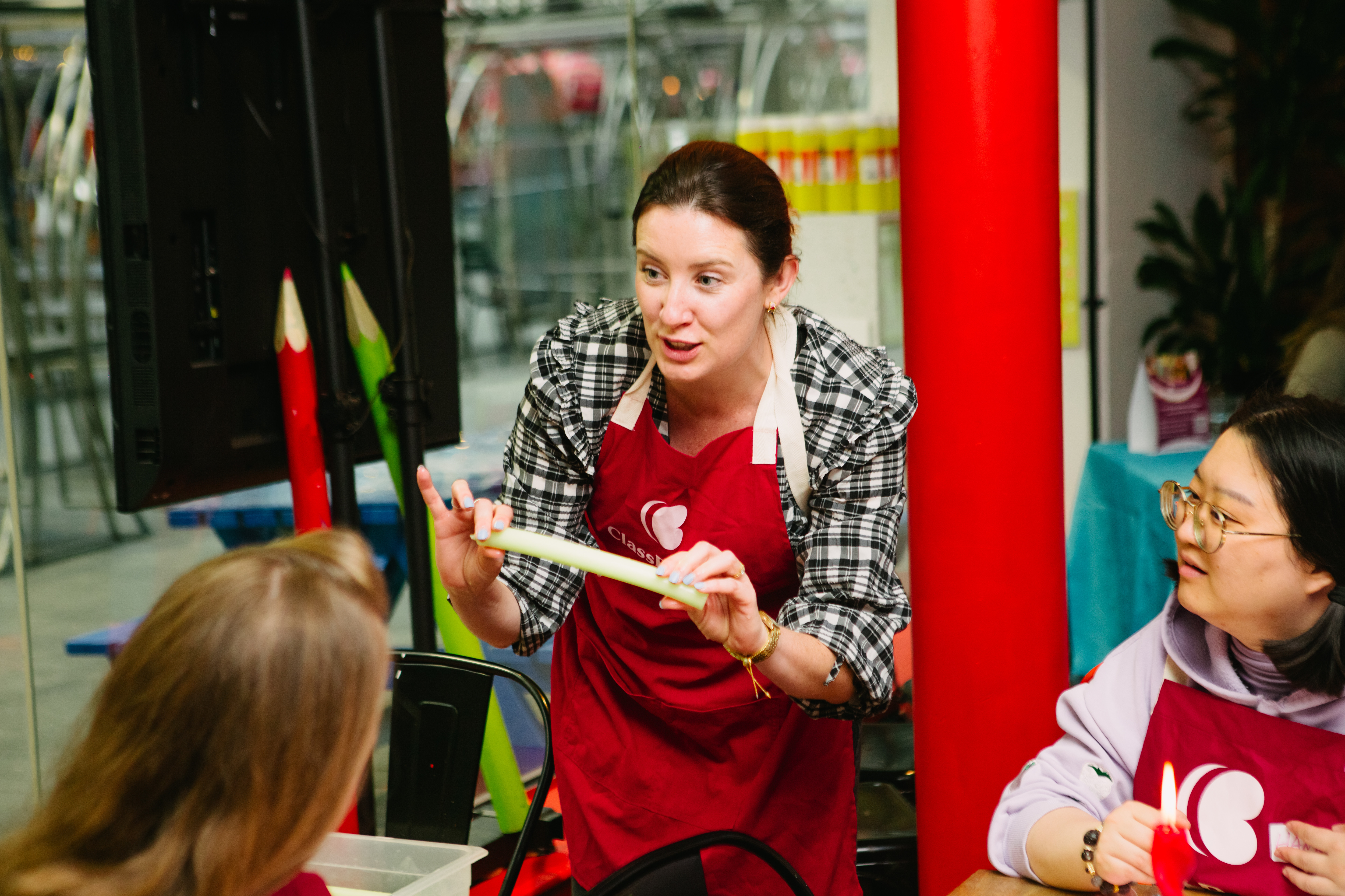 A woman is teaching a group of people how to make bendy candles